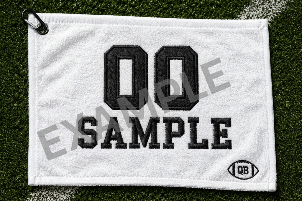 White football towel with satin stitch embroidery showing 23 Johnson in black thread on grass background