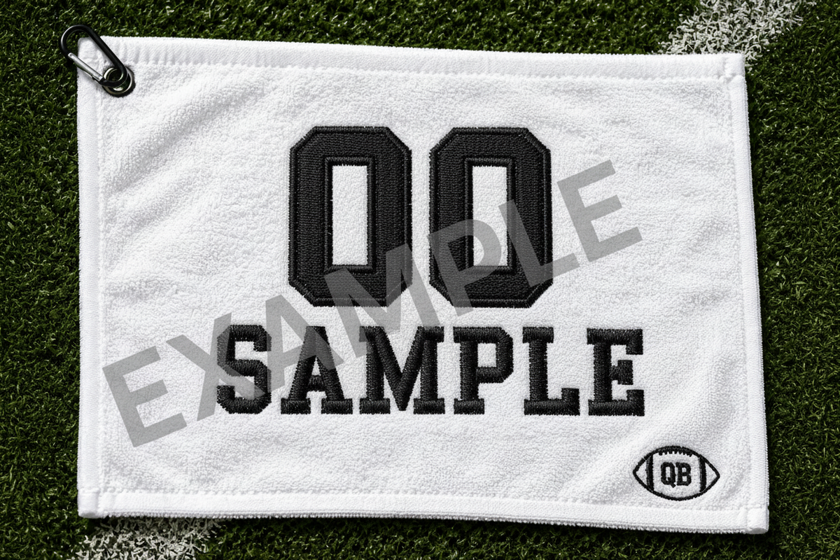 White football towel with satin stitch embroidery showing 23 Johnson in black thread on grass background