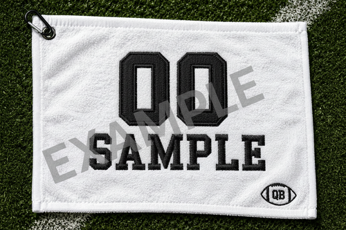 White football towel with satin stitch embroidery showing 23 Johnson in black thread on grass background